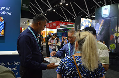 Visitors enjoying menu inspiration and seafood discussions with Blue Wave team